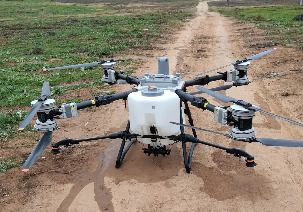 Dron agrícola DJI Agras T100 de DroneTech en terreno, con estanque de 100 litros